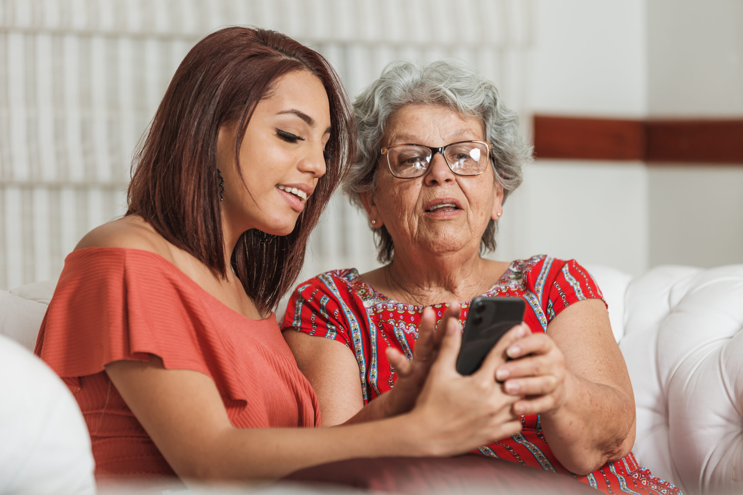 mother and adult daughter fiddling with cellphone in living room